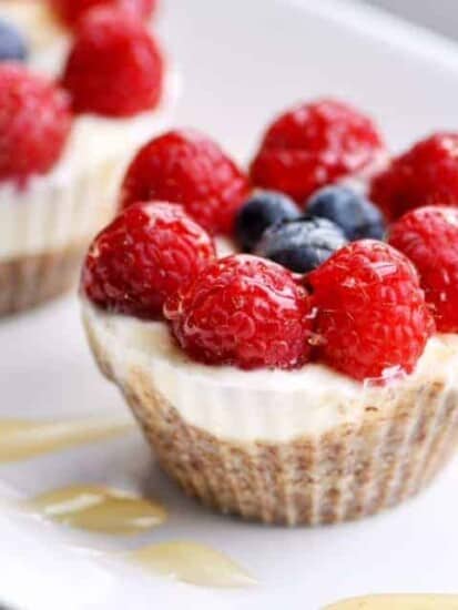 close up image of a frozen yogurt fruit cup with an almond meal crust topped with raspberries, blueberries, and honey