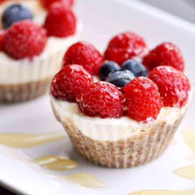 close up image of a frozen yogurt fruit cup with an almond meal crust topped with raspberries, blueberries, and honey