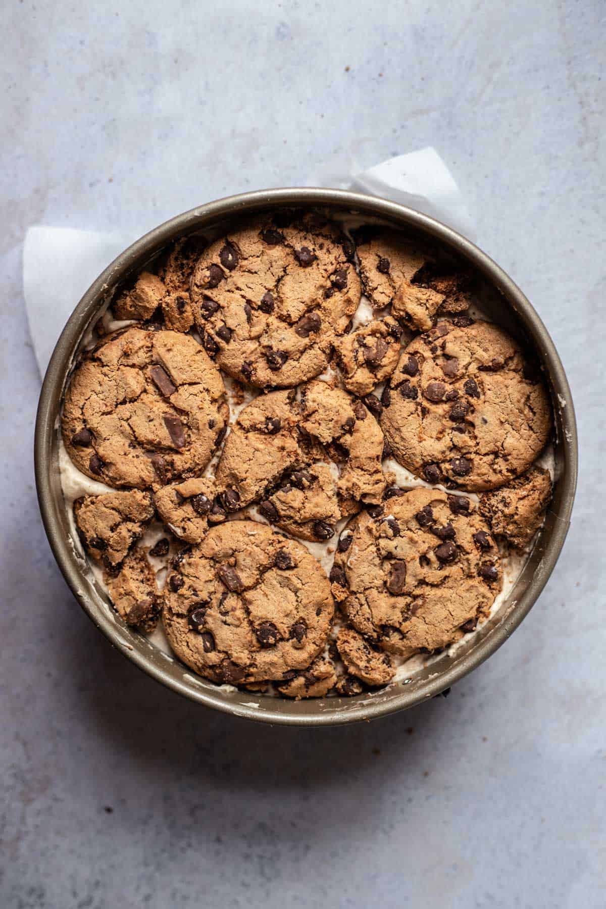 a layer of chocolate chip cookies over mocha chocolate ice box cake filling in a spring form pan 