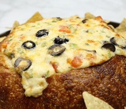 Sourdough Bread Bowl Cheese Dip Recipe on a plate surrounded by tortilla chips.