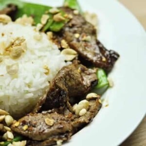 A plate of beef with snow peas surrounding a mound of white rice.