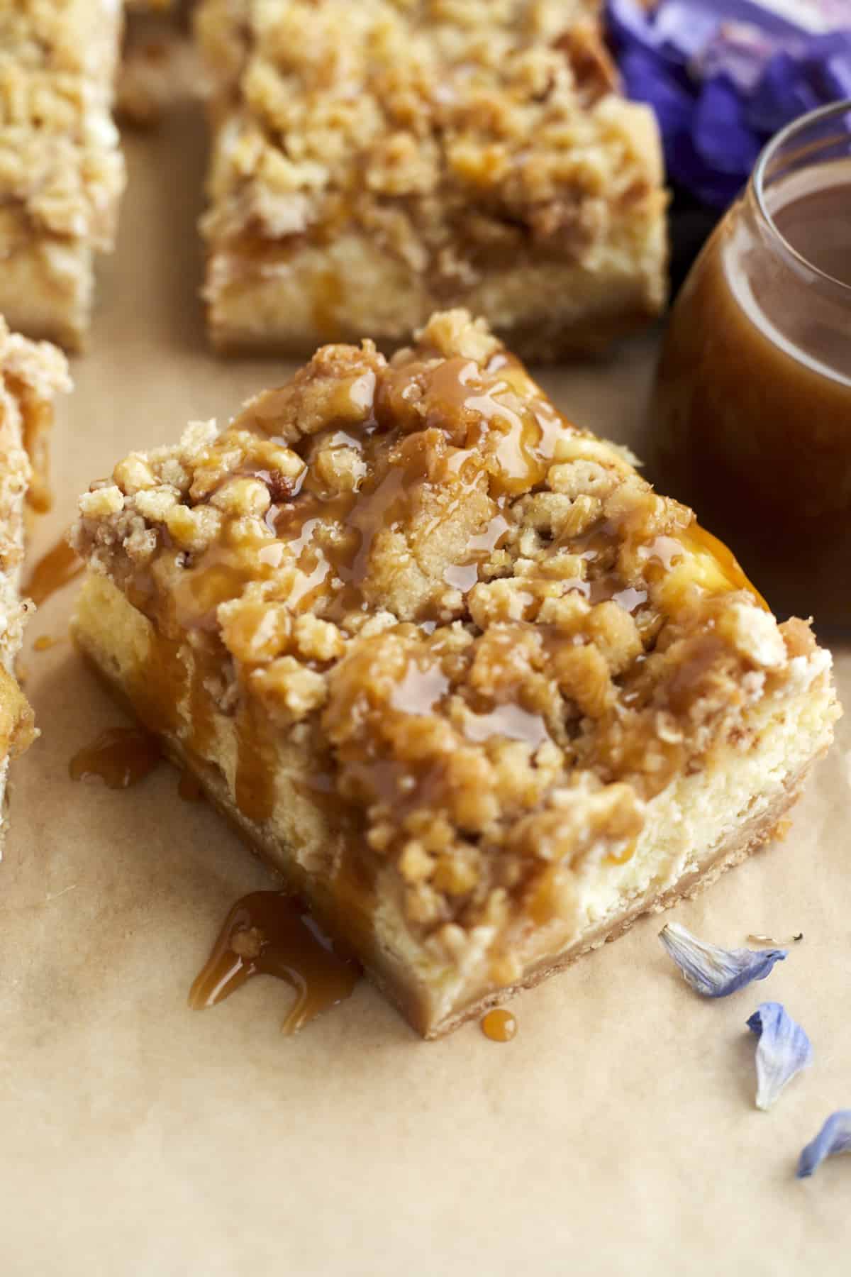 close up image of a caramel apple cheesecake bar topped with caramel 