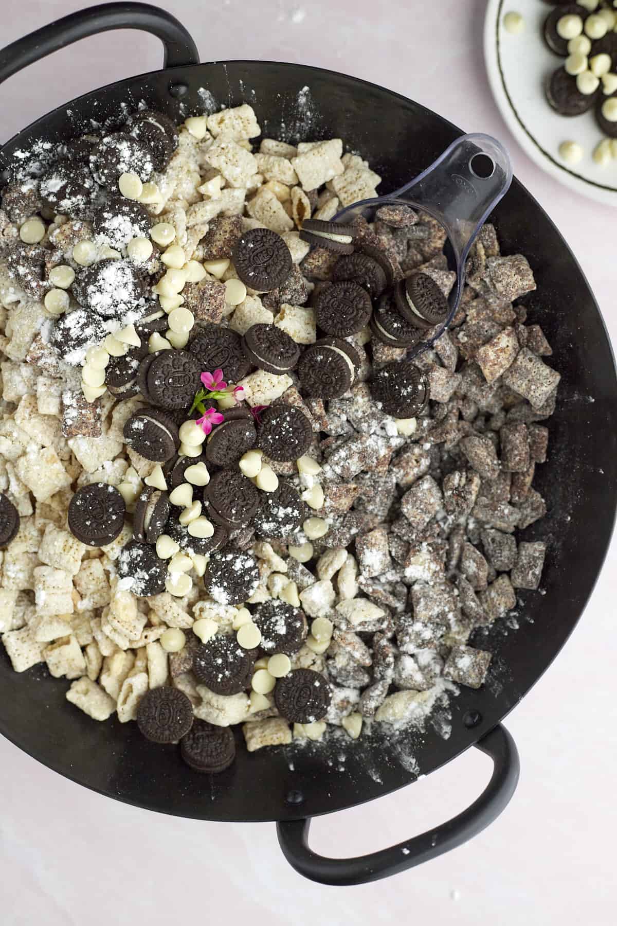a skillet full of cookies and cream muddy buddies with mini Oreos and white chocolate chips