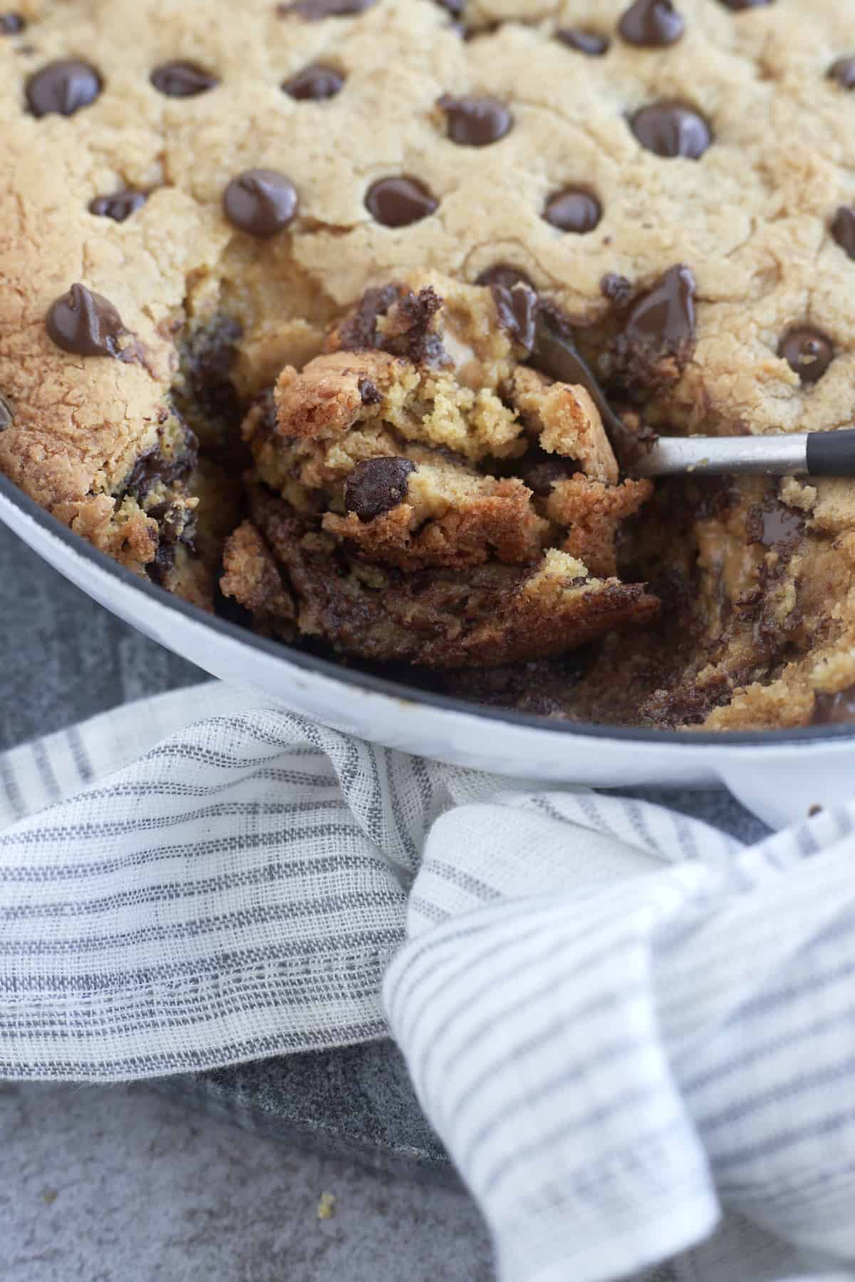 a spoon scooping a bite from a peanut butter chocolate chip cookie skillet