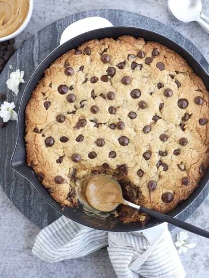 peanut butter chocolate chip cookie skillet with a bite missing and a peanut butter coated spoon