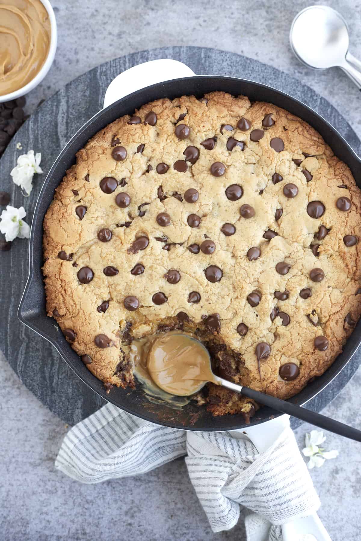 peanut butter chocolate chip cookie skillet with a bite missing and a spoon coated in peanut butter in its place