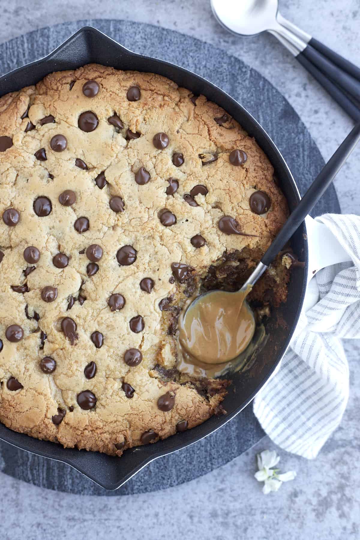 peanut butter chocolate chip cookie skillet with bites missing and a peanut butter coated spoon in their place