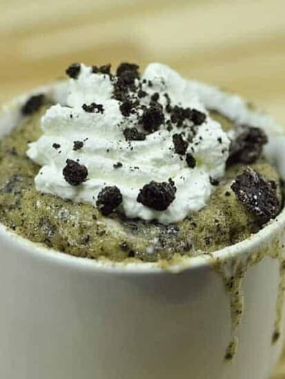 Cookies and cream mug cake topped with whipped cream and Oreo pieces