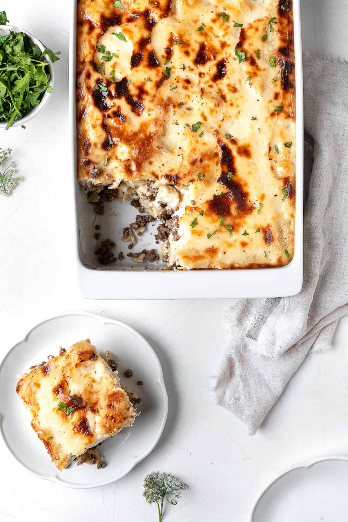 a casserole dish of macarona béchamel with a slice on a white plate