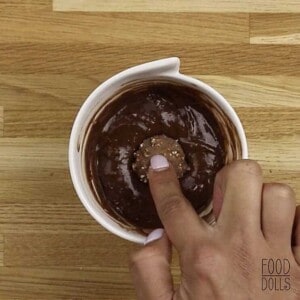 A finger pushing a Ferrero Rocher candy into chocolate hazelnut mug cake batter.