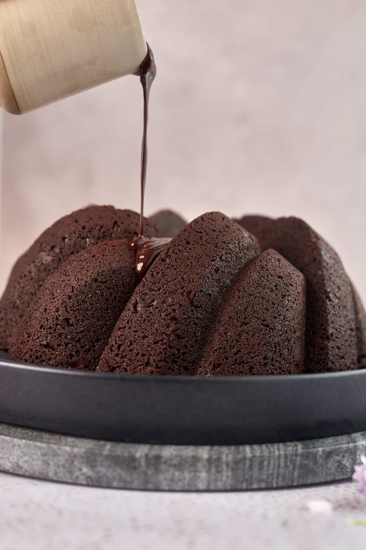 bundt cake being topped with chocolate icing