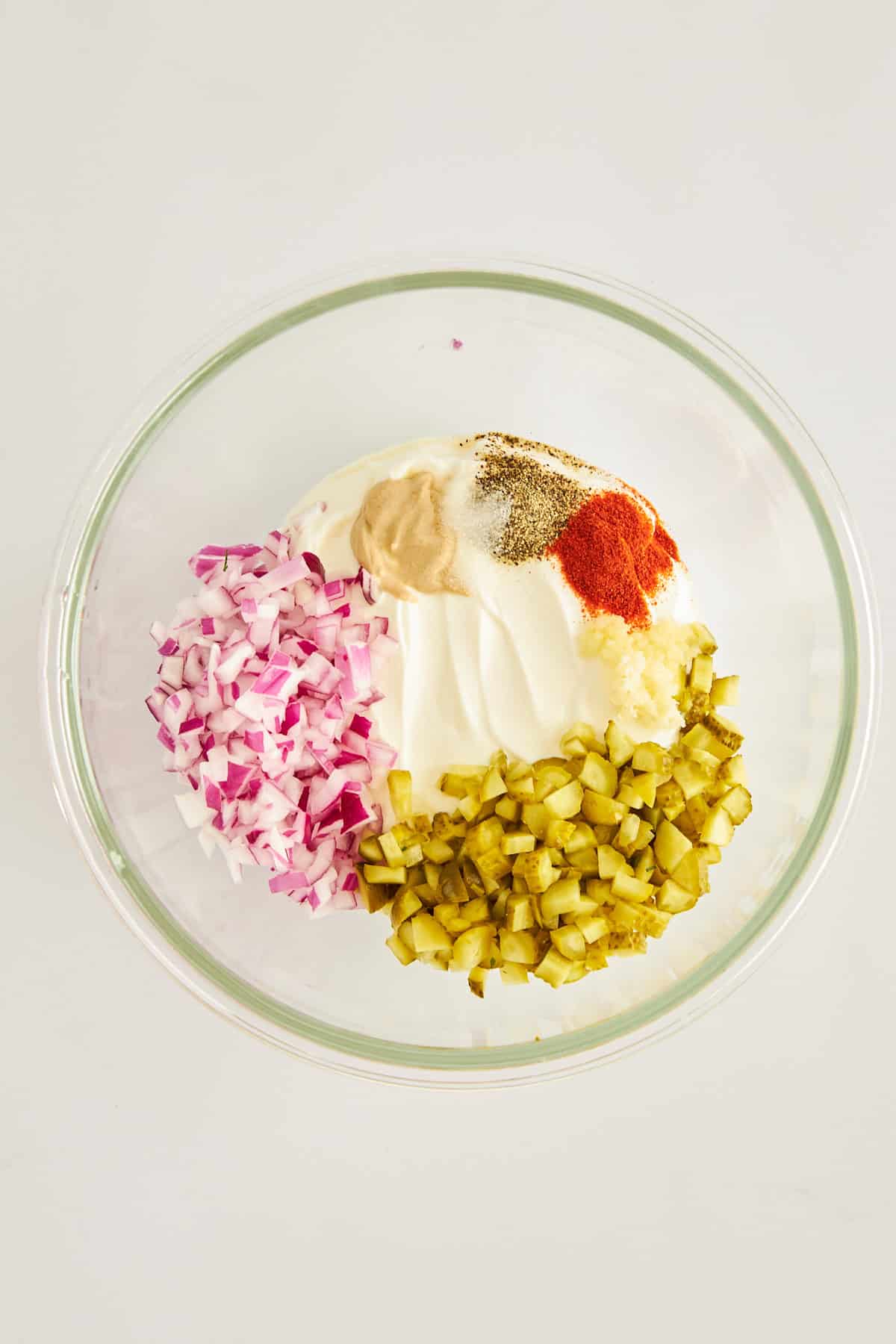 Labneh, pickles, red onion, and seasonings in a bowl.