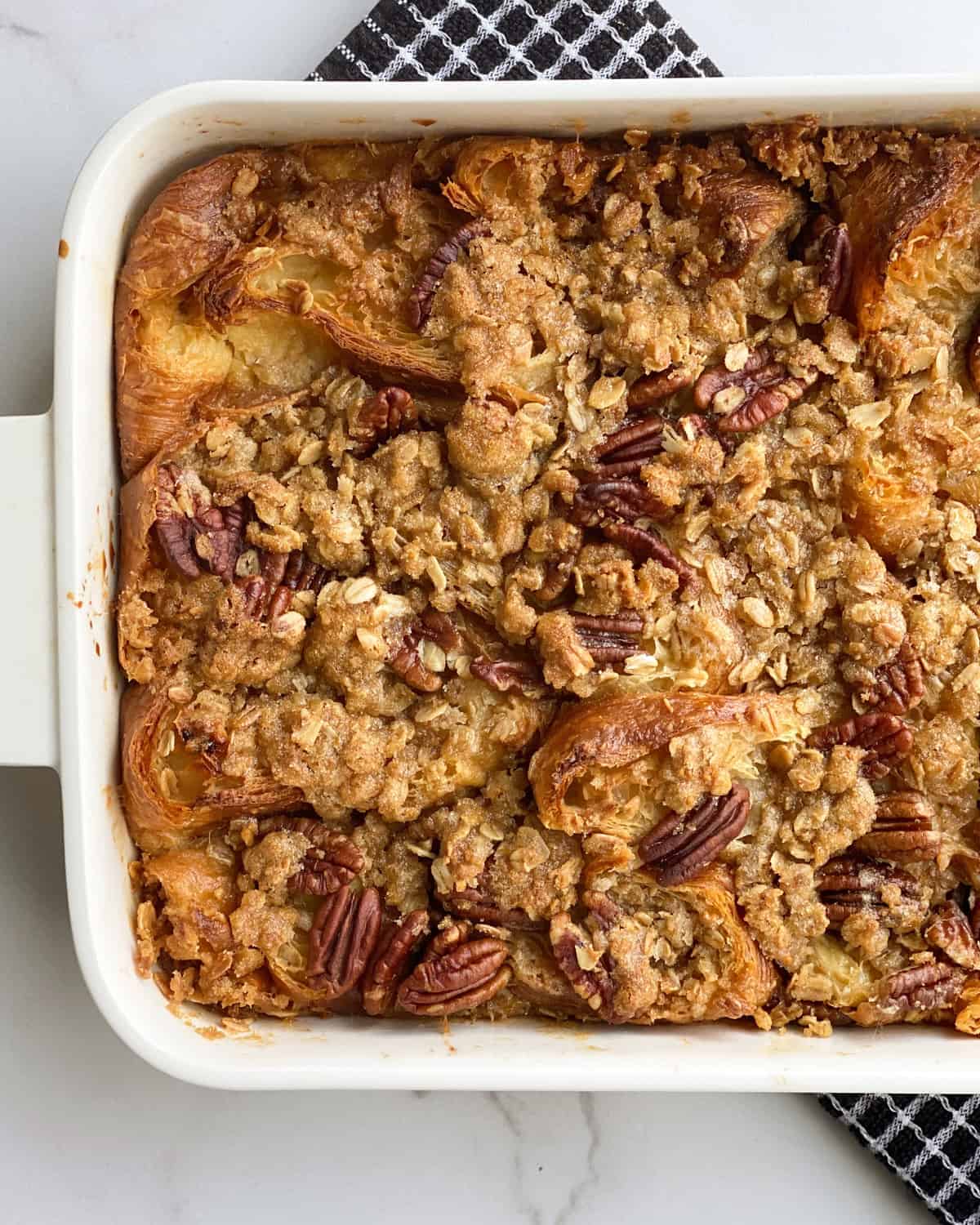 overhead image of pecan pie croissant bread pudding in a white baking dish