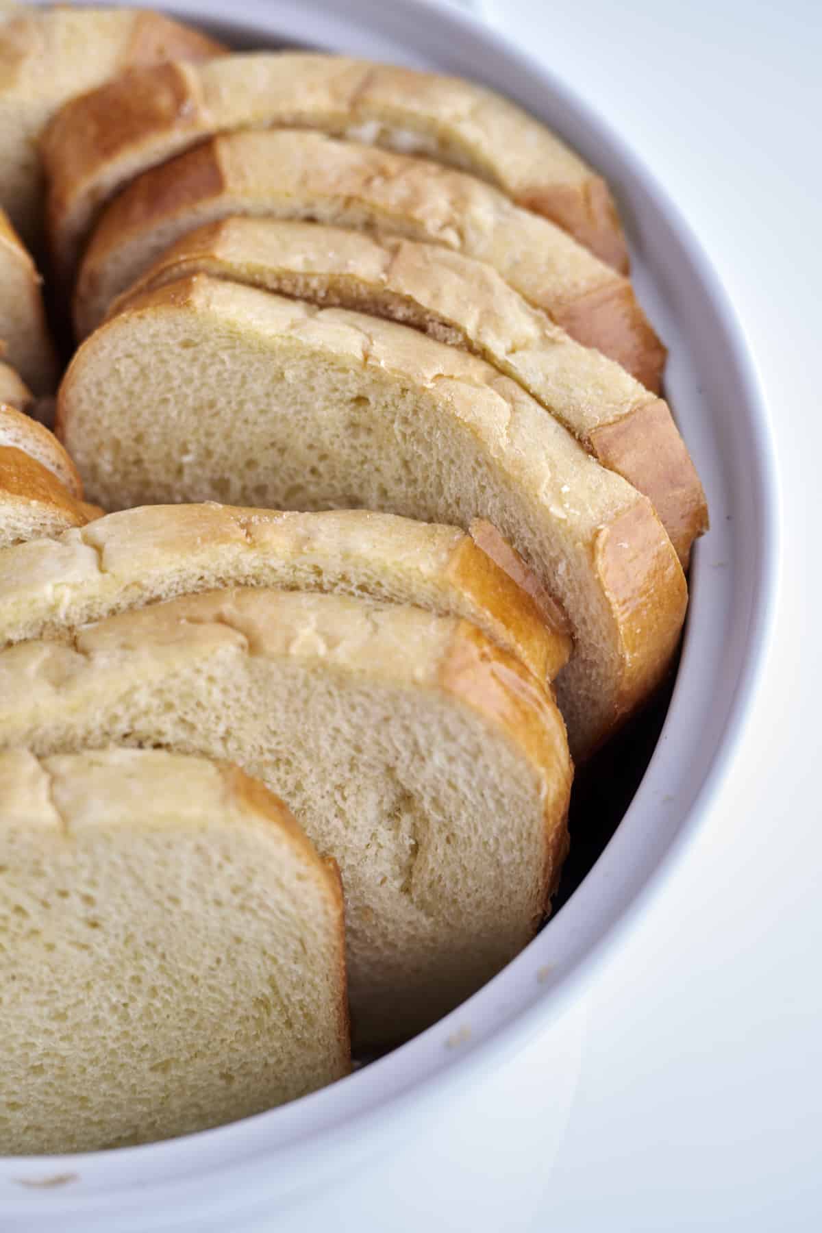 sliced brioche bread in a white baking dish ready to be baked