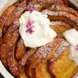 a baking dish with cinnamon french toast topped with powdered sugar and marscapone