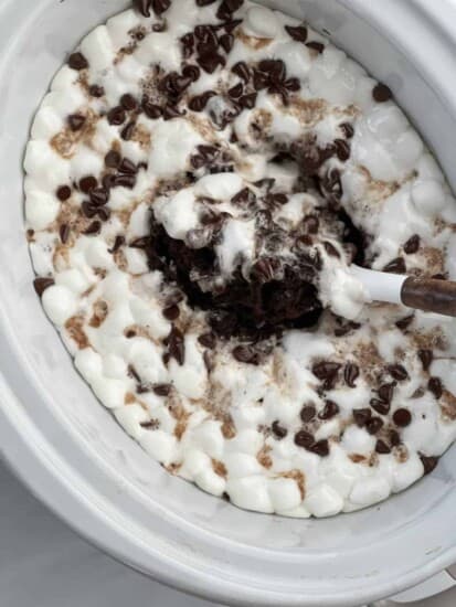 a spoon dipping into slow cooker s'mores chocolate cake