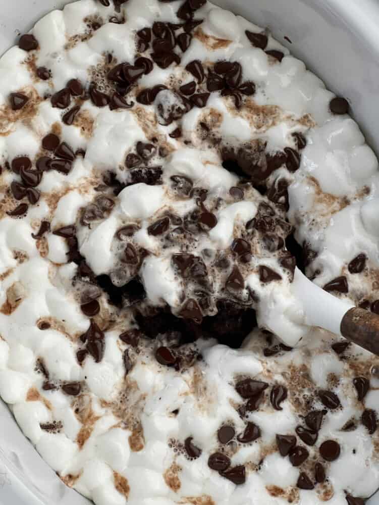 slow cooker chocolate smores cake being scooped out of a slow cooker