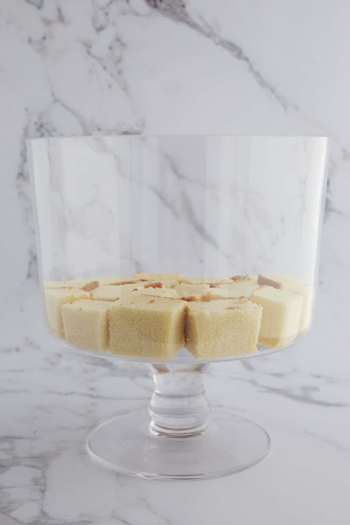Cubes of pound cake in the bottom of a trifle dish. 