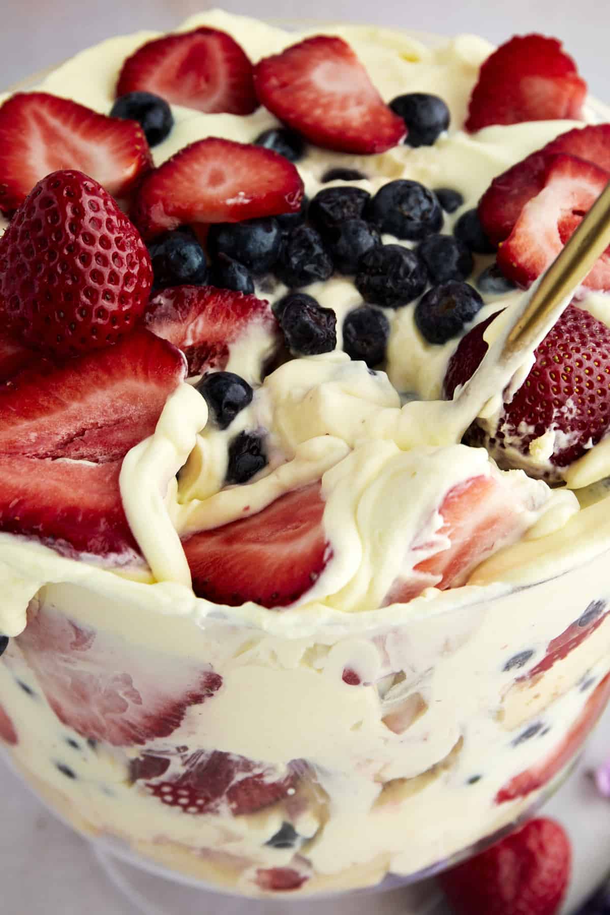 Overhead image of a summer berry trifle with a serving spoon dipping in. 