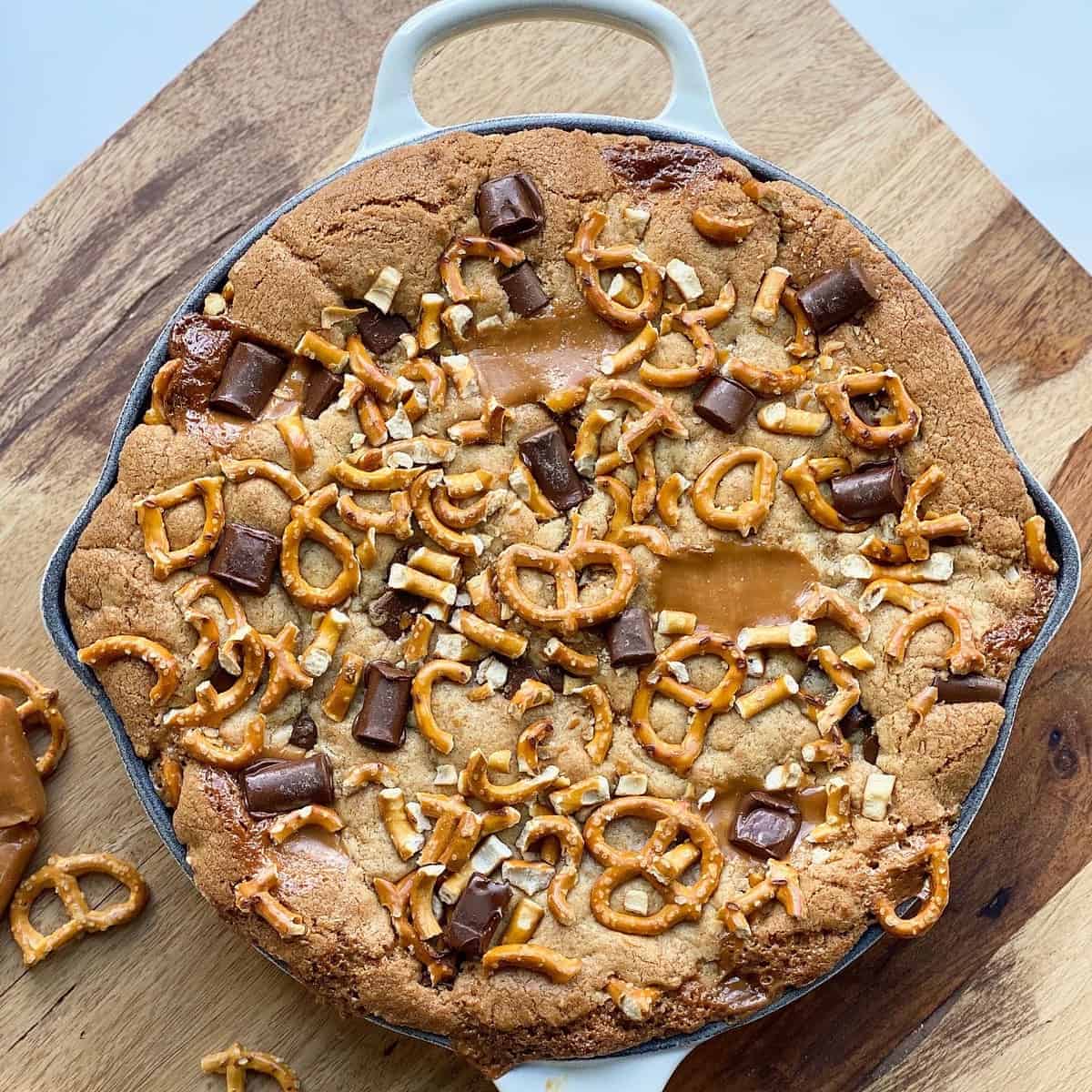 Overhead image of a salted caramel cookie skillet topped with caramel and pretzels.