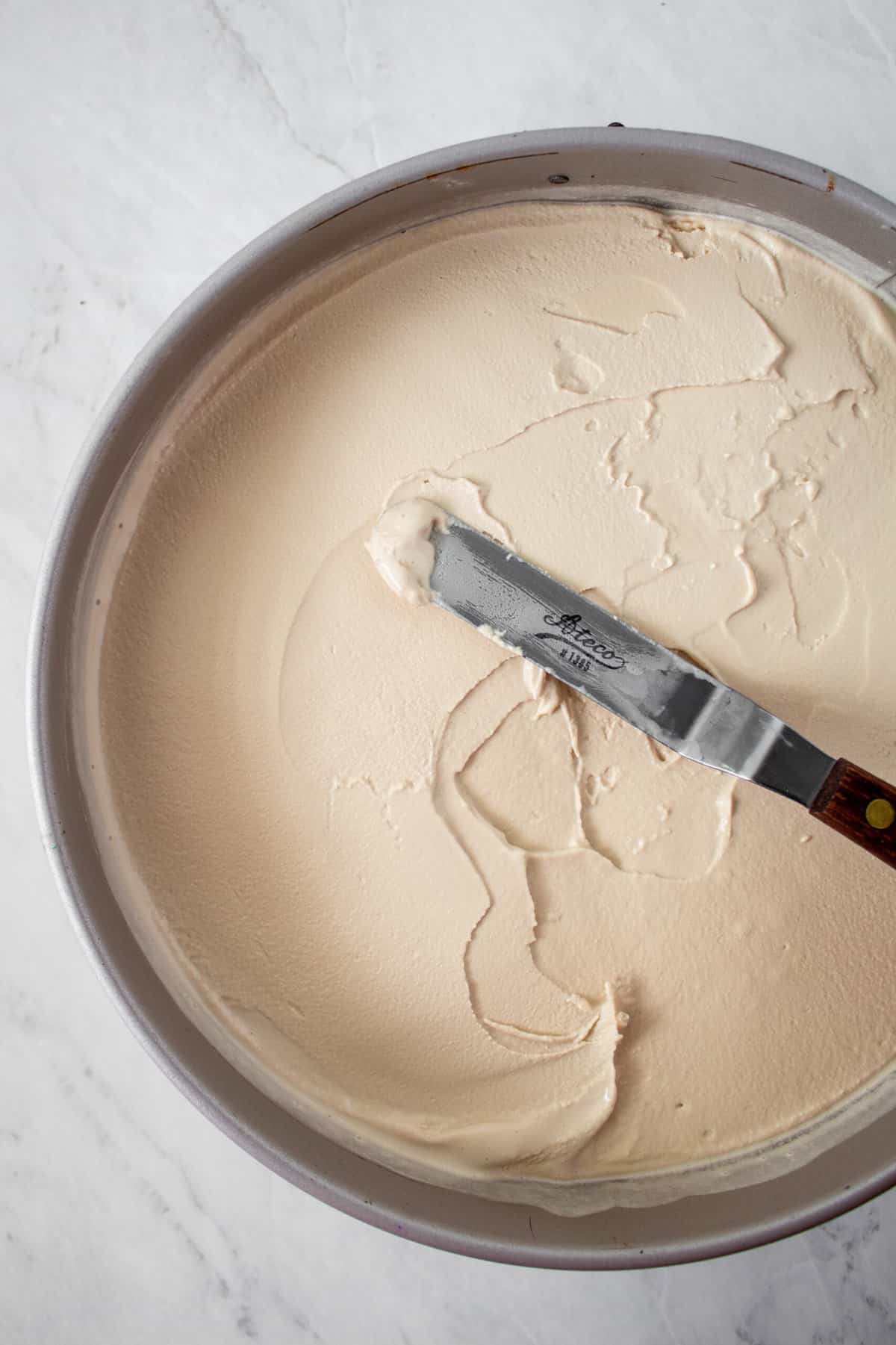 coffee ice cream being smoothed on top of chocolate crust