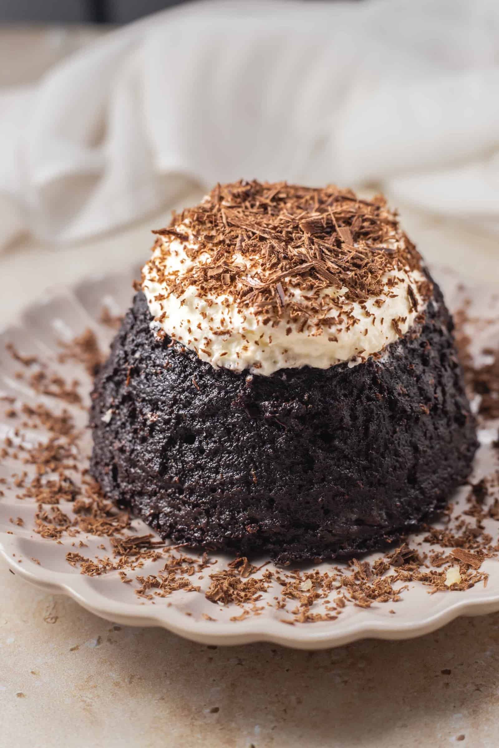 Hazelnut chocolate lava cake on a plate topped with cream and chocolate shavings