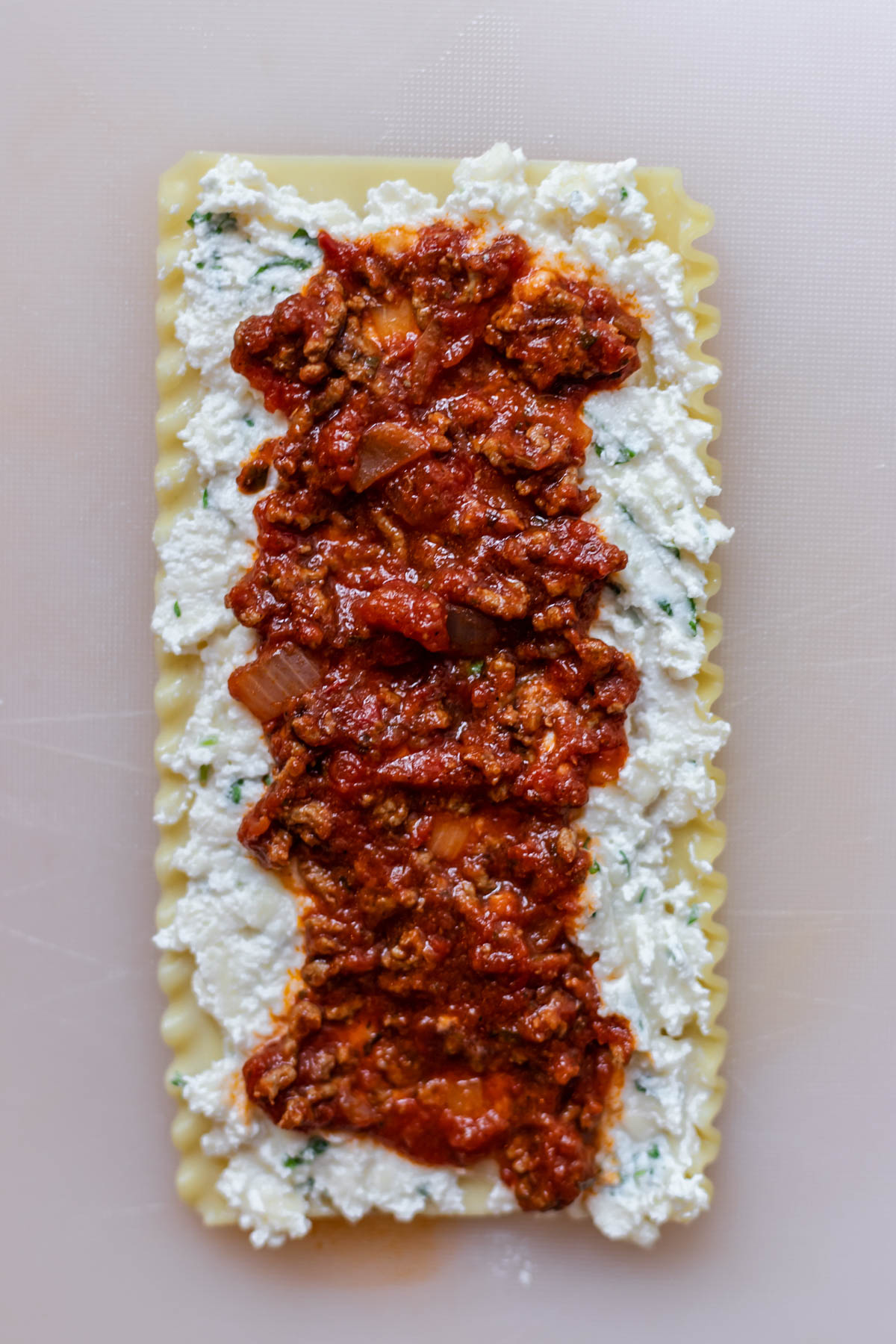 a sheet of lasagna layered with ricotta cheese and marinara sauce