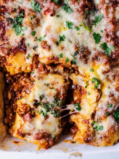 close up image of baked lasagna rolls in a baking dish