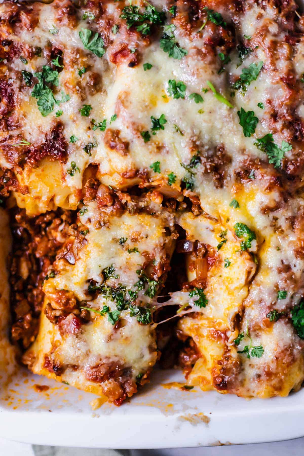 close up image of baked lasagna rolls in a baking dish 