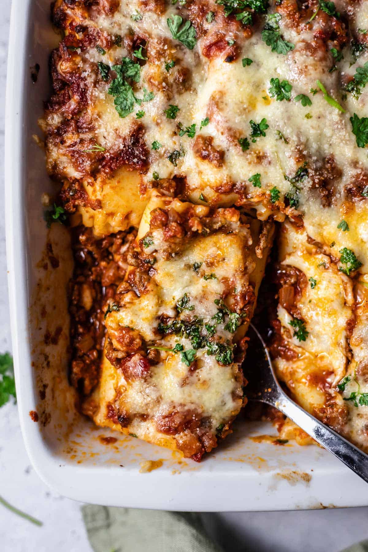 a baked lasagna roll being lifted up with a serving spoon