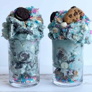 two jars of edible cookie monster cookie dough topped with Oreos and chocolate chip cookies