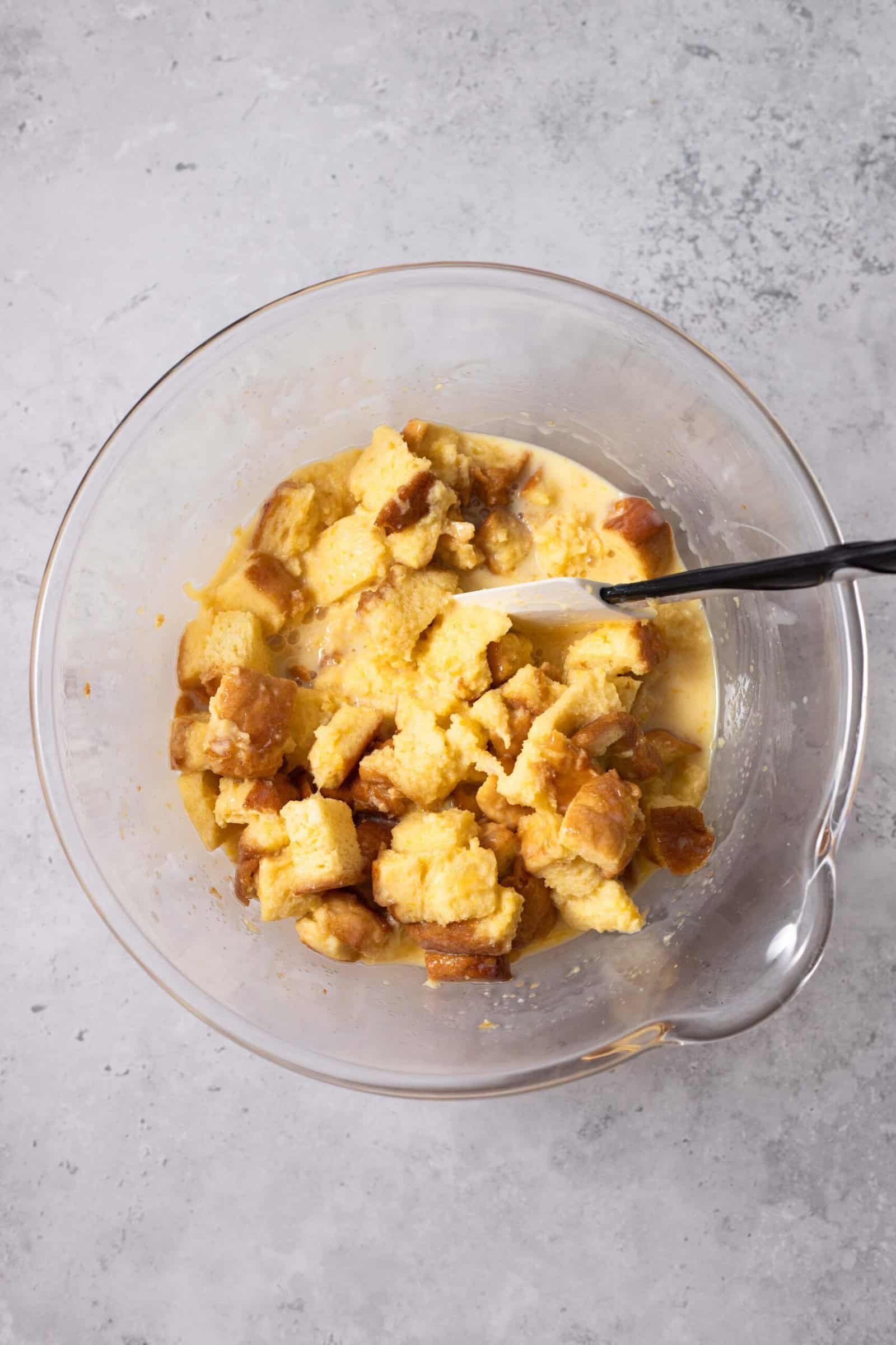 bread pieces being combined with egg yolks, whole milk, sweetened condensed milk, and sugar