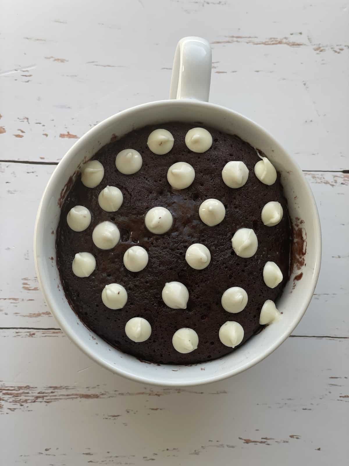 Chocolate mug cake topped with white chocolate chips.