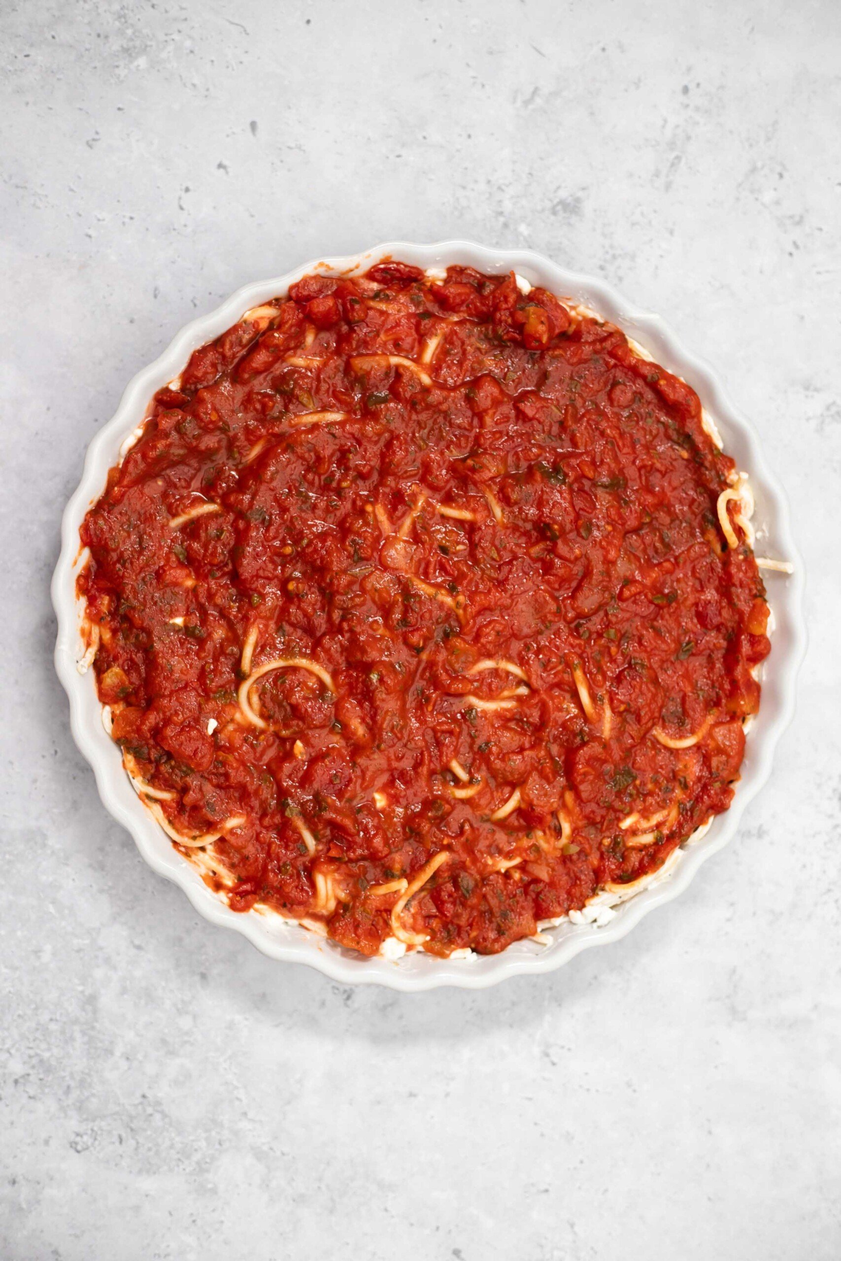 marinara sauce layered over noodles in a casserole dish