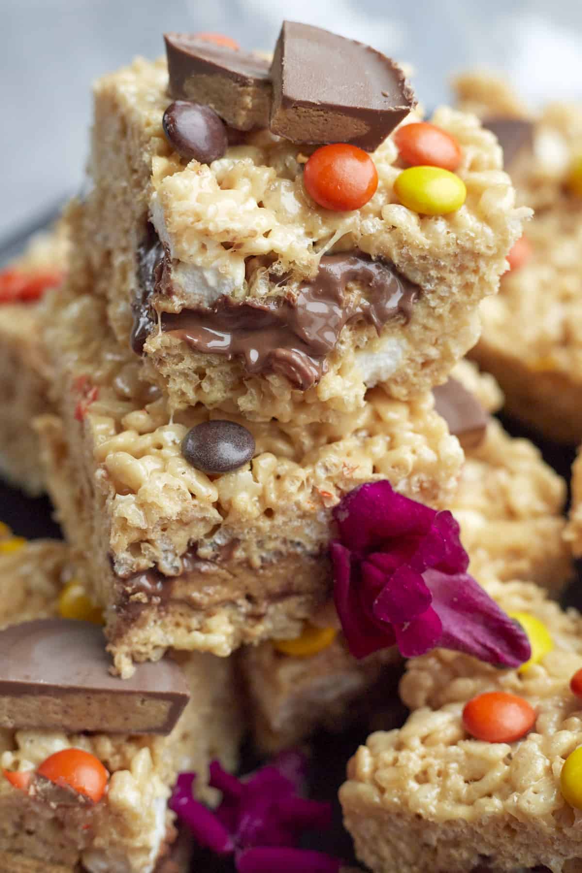 Peanut Butter Rice Krispie Treats stacked on top of each other with a bite taken out of the treat on top.