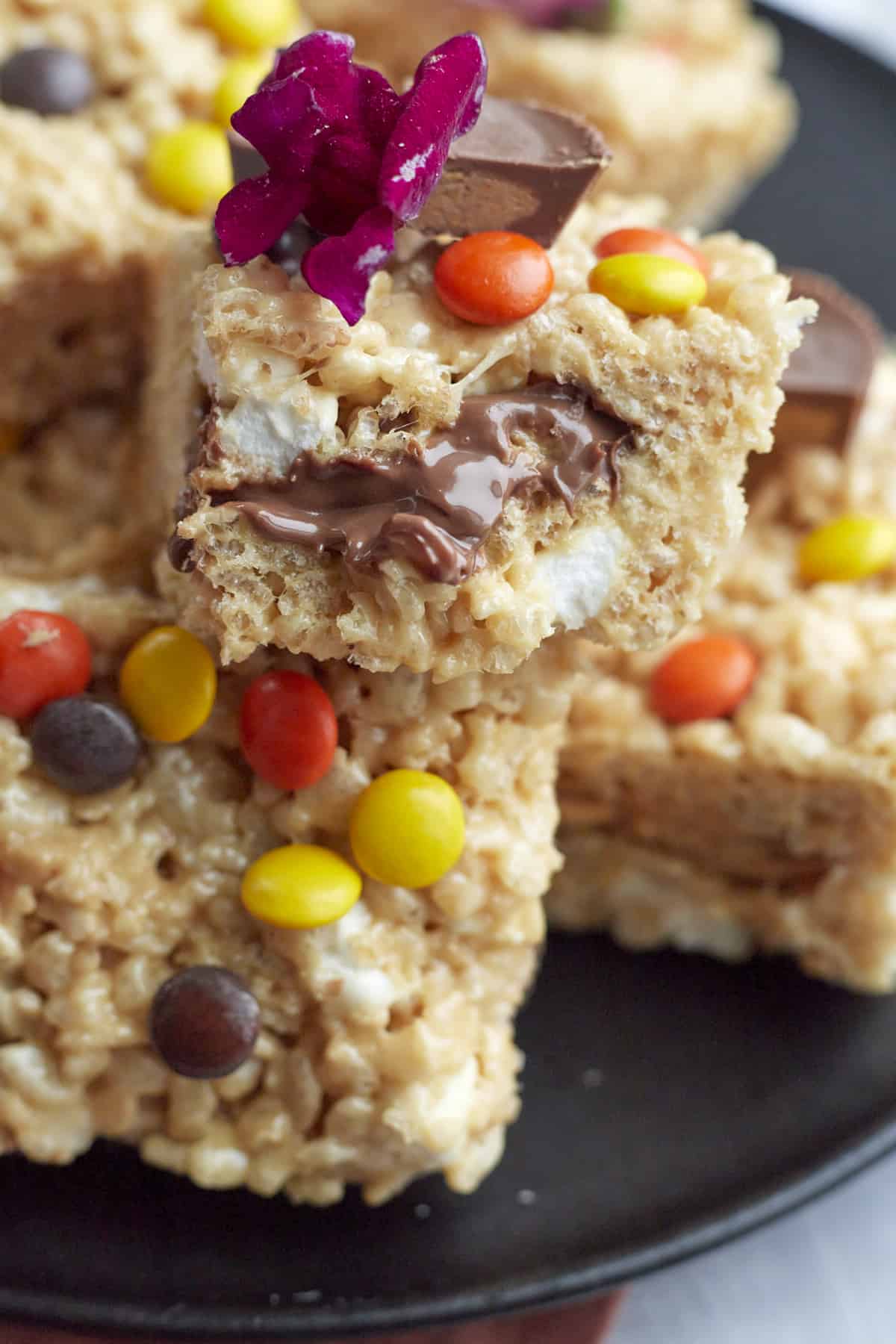 close up image of Peanut Butter Rice Krispie Treats stacked on top of each other with a bite taken out of the treat on top