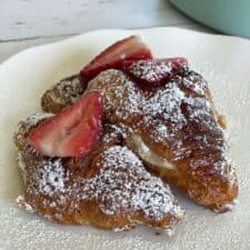 two strawberry cheesecake french toast croissants on a plate
