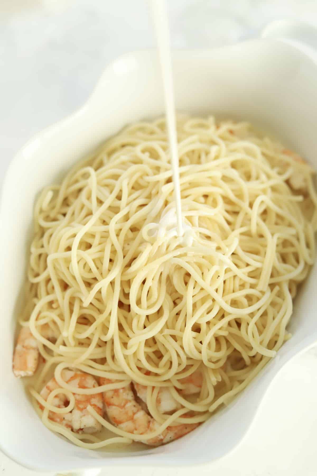 cooked shrimp in a baking dish with spaghetti and heavy cream