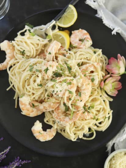overhead garlic shrimp scampi on a plate with spoon and fresh lemon slices