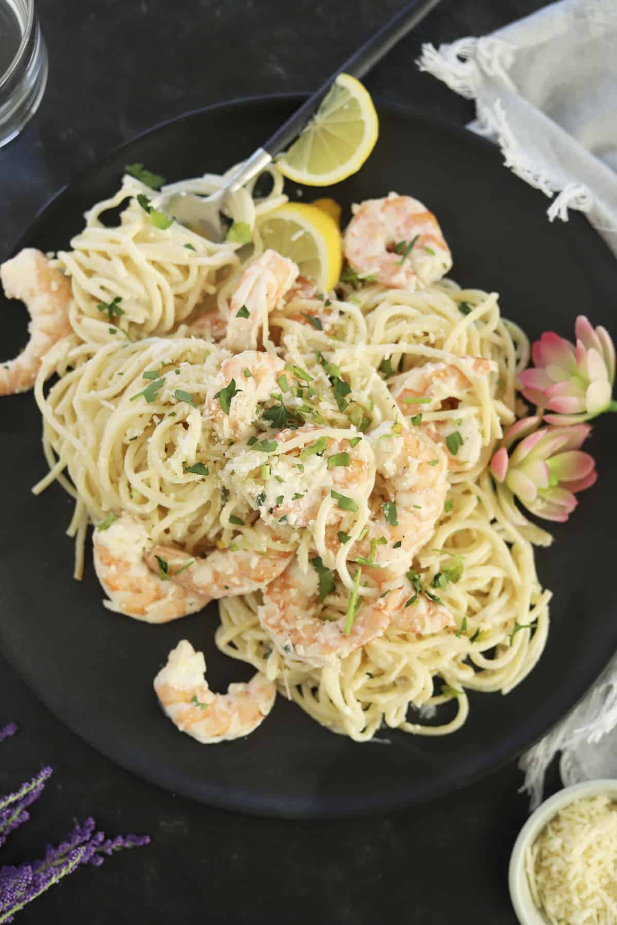baked garlic shrimp scampi on a plate with spoon and lemons