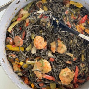Overhead image of a pot of Cajun shrimp and sausage pasta with black squid ink spaghetti.
