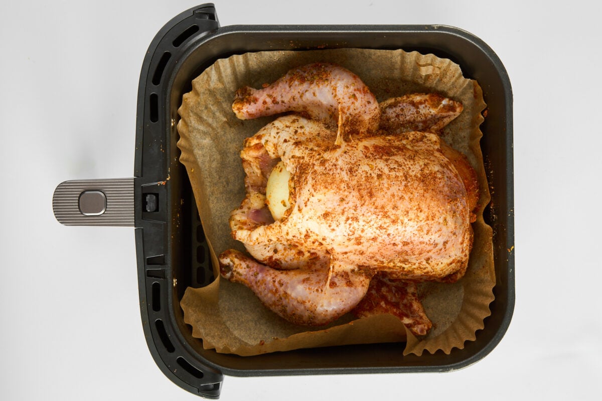 A raw whole chicken in an air fryer.