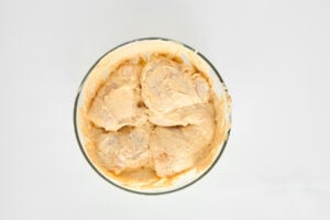 Raw chicken breasts marinating in a hummus mixture.