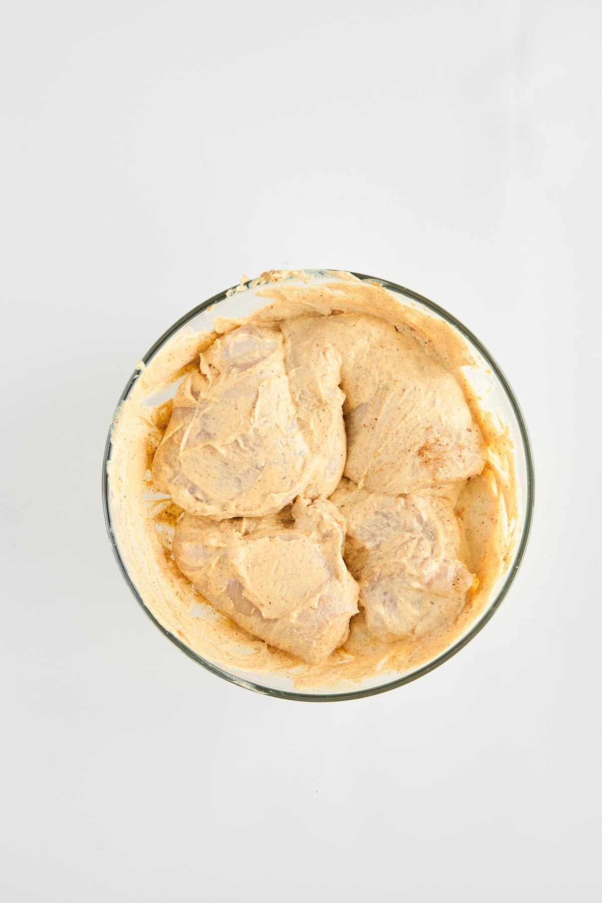 Raw chicken breasts marinating in a hummus mixture. 