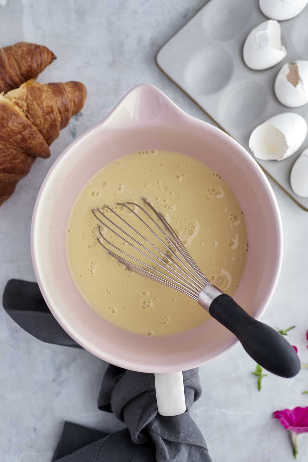 a liquid measuring cup with an egg and milk french toast mixture and a whisk sticking out