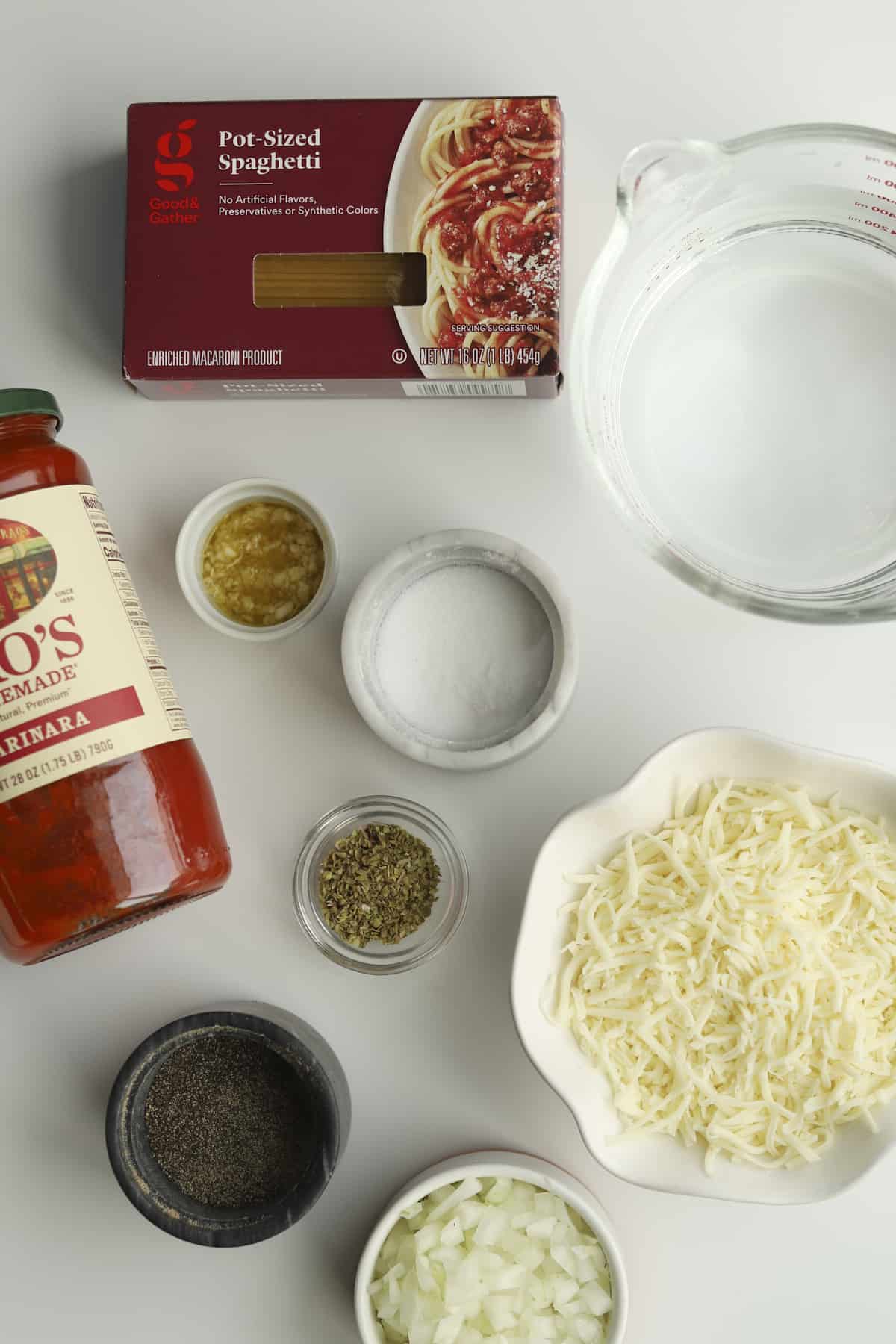 a box of pot-sized spaghetti noodles, water, salt, Italian spices, garlic, a jar of Marinara, pepper, diced onions, shredded Mozzarella
