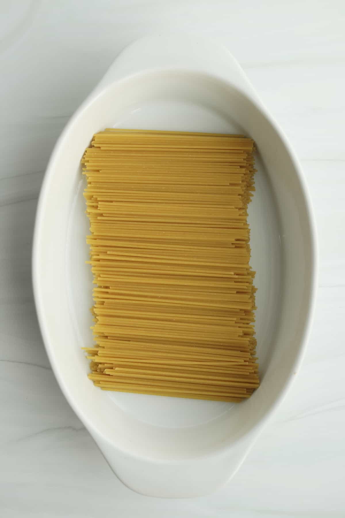 overhead image of raw spaghetti pasta in a baking dish