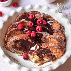 a platter of churro french toast topped with chocolate sauce and raspberries