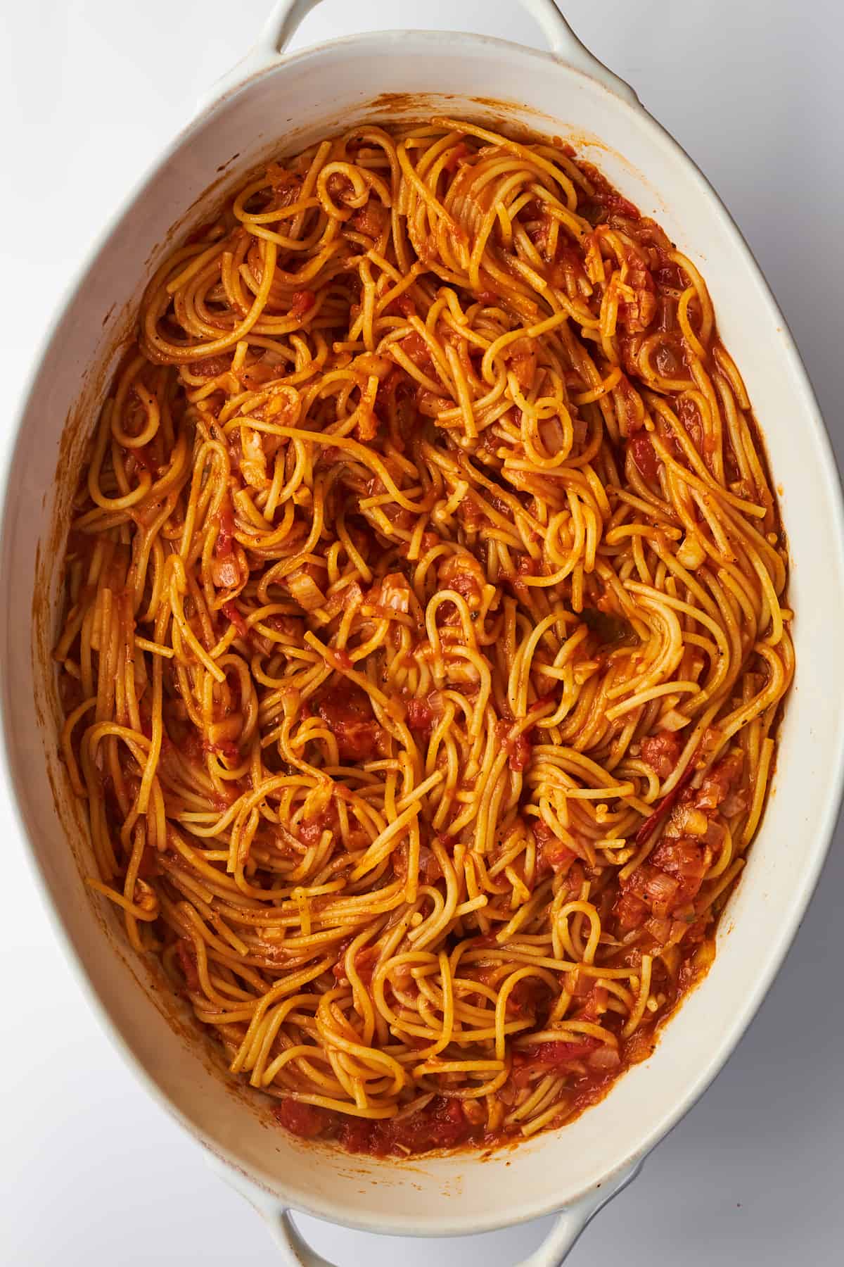 An oval baking dish full of baked spaghetti.