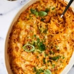 An oval baking dish full of oven baked spaghetti.